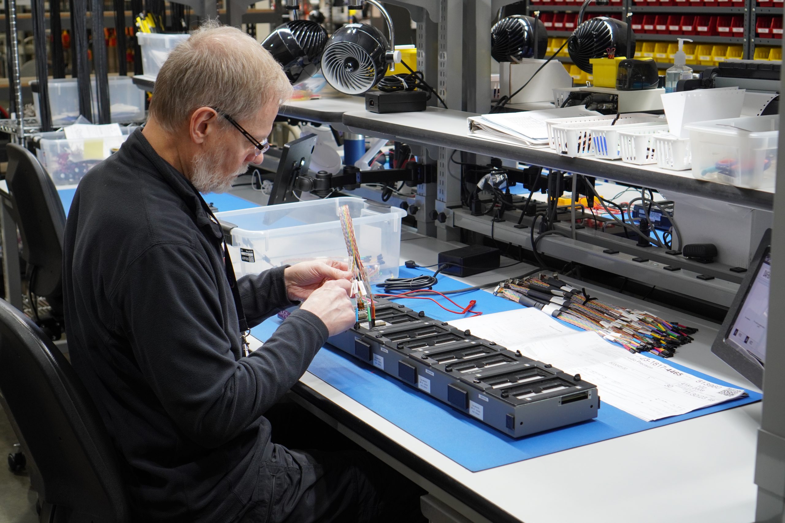 A male employee tests as cable assembly through electronic machinery.
