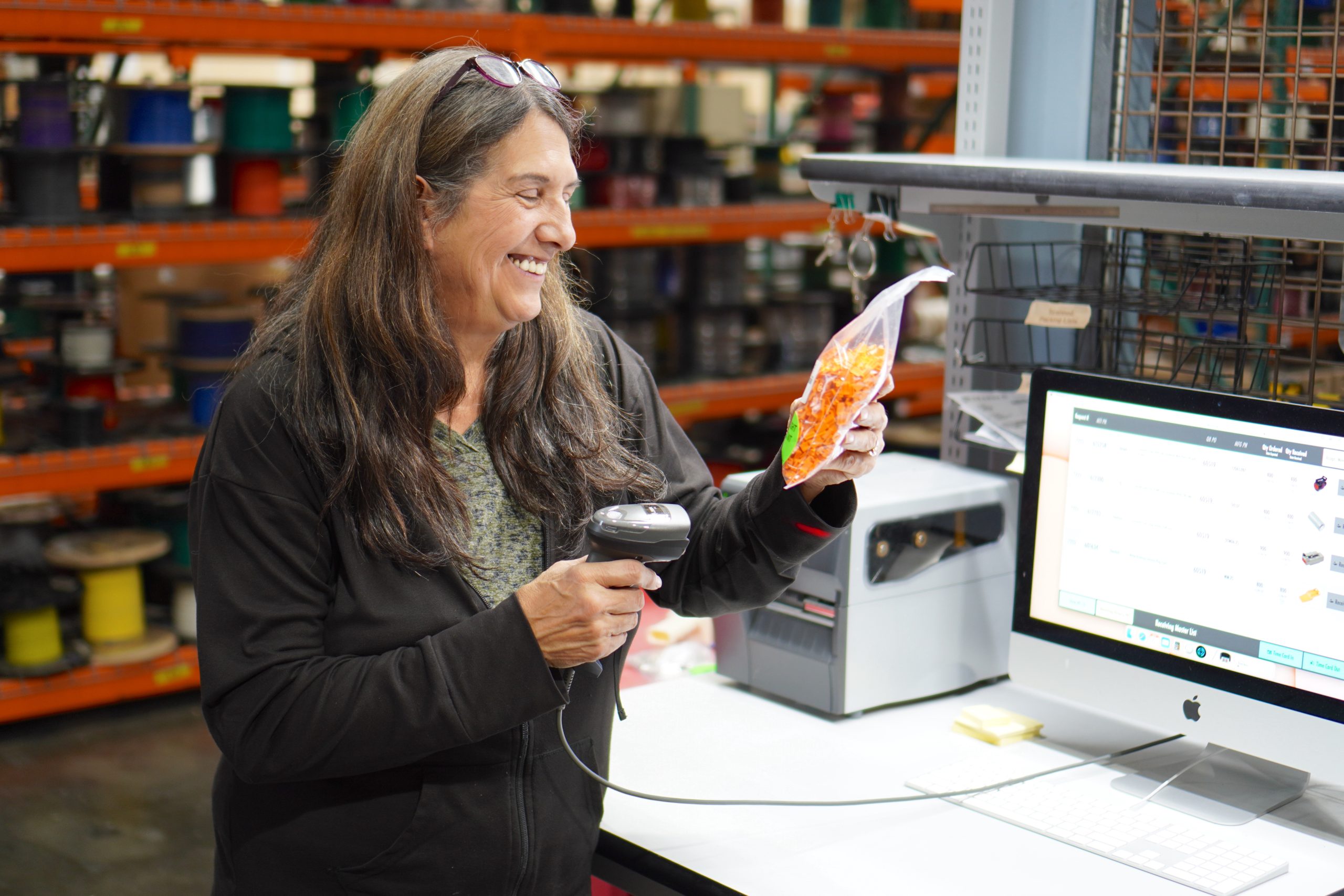 A female employee smiles as she holds an item at receiving.