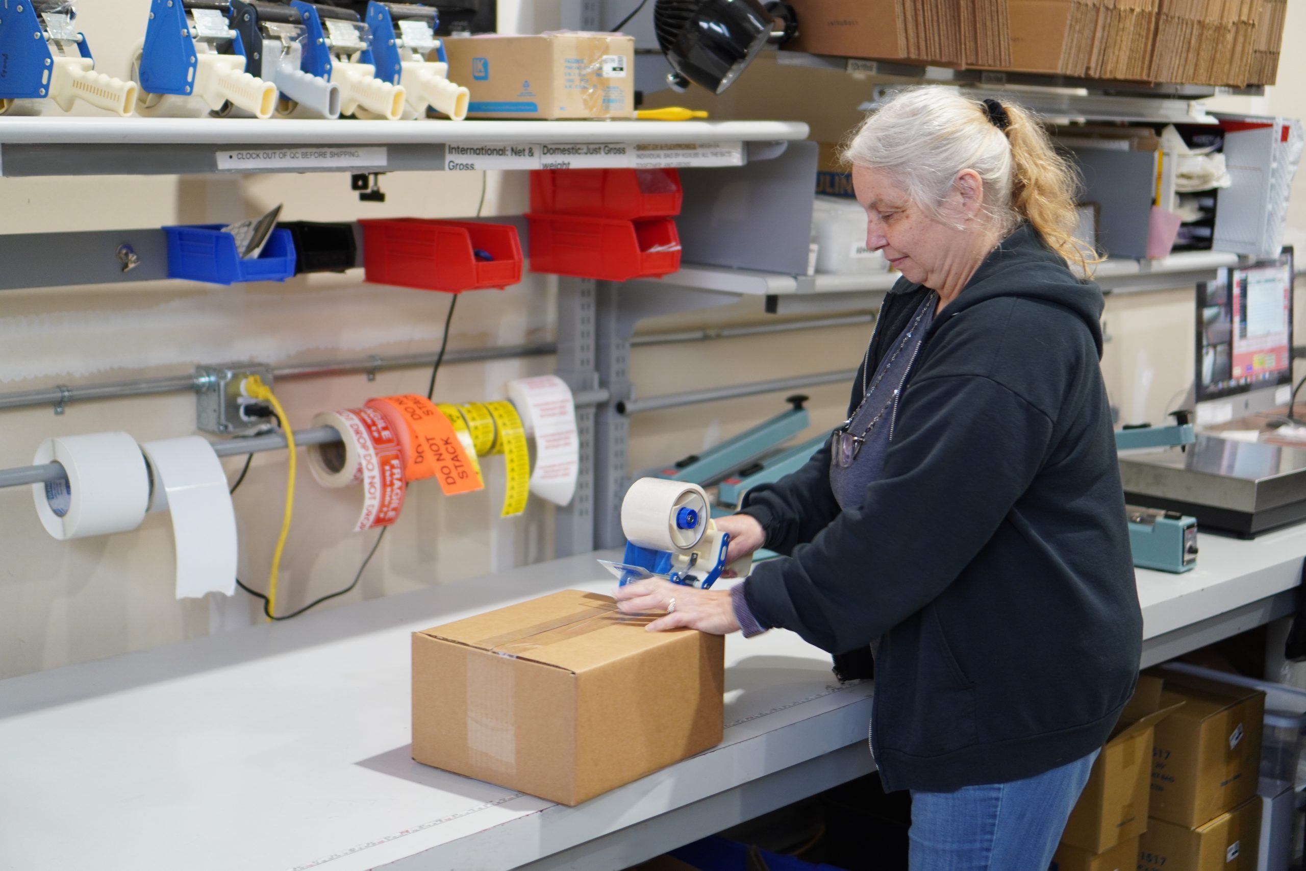 A female employee tapes up a box as it is readied for shipping.